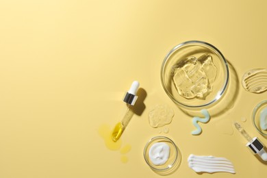 Petri dishes with cosmetic products and pipettes on yellow background, flat lay. Space for text