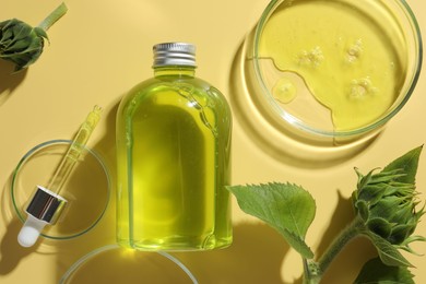 Photo of Petri dishes with cosmetic product, bottle, pipette and sunflowers on yellow background, flat lay