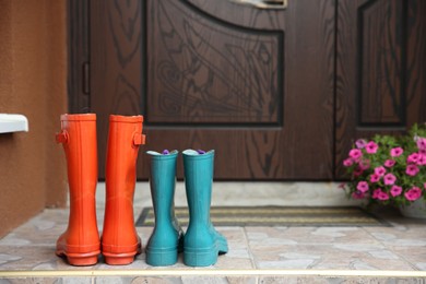 Photo of Two pairs of rubber boots on doorstep near entrance outdoors