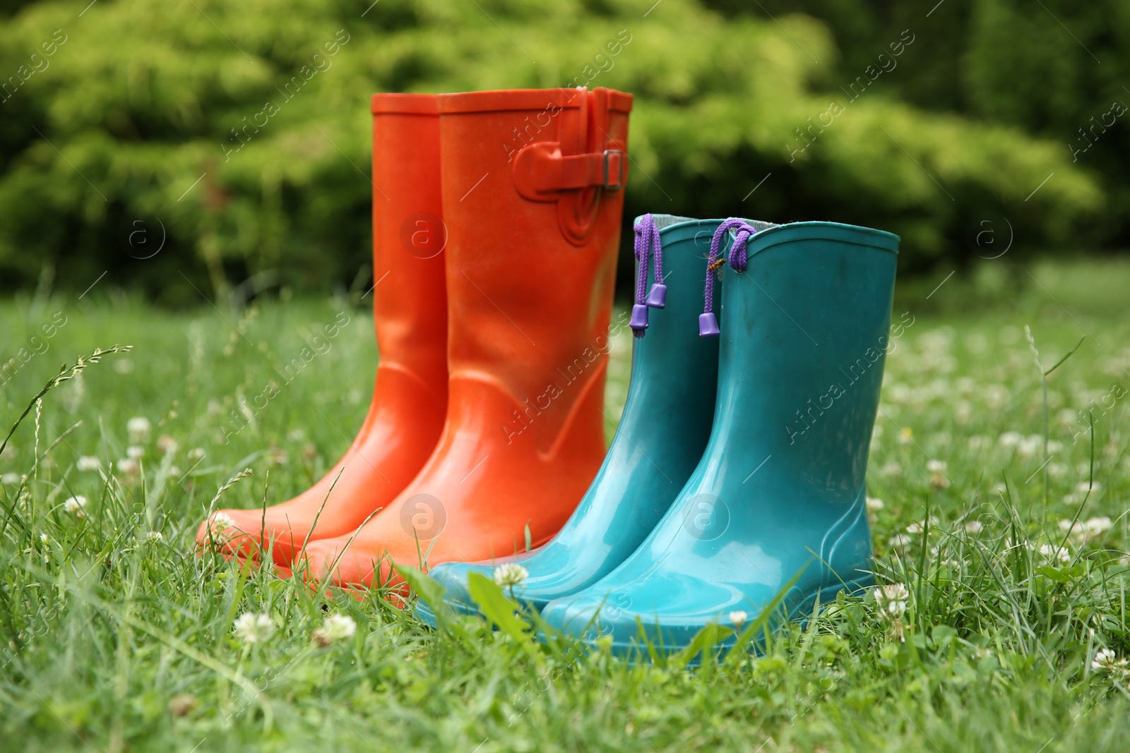 Photo of Two pairs of rubber boots on green grass outdoors