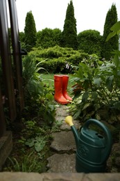 Photo of Orange rubber boots and watering can outdoors