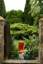 Photo of Orange rubber boots and watering can outdoors