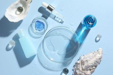 Photo of Petri dishes with cosmetic product, pipette and seashells on light blue background, flat lay