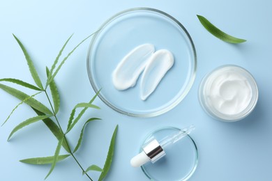 Photo of Petri dishes with cosmetic product, pipette and leaves on light blue background, flat lay