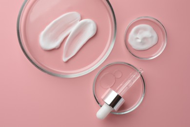 Petri dishes with cosmetic products and pipette on pink background, flat lay