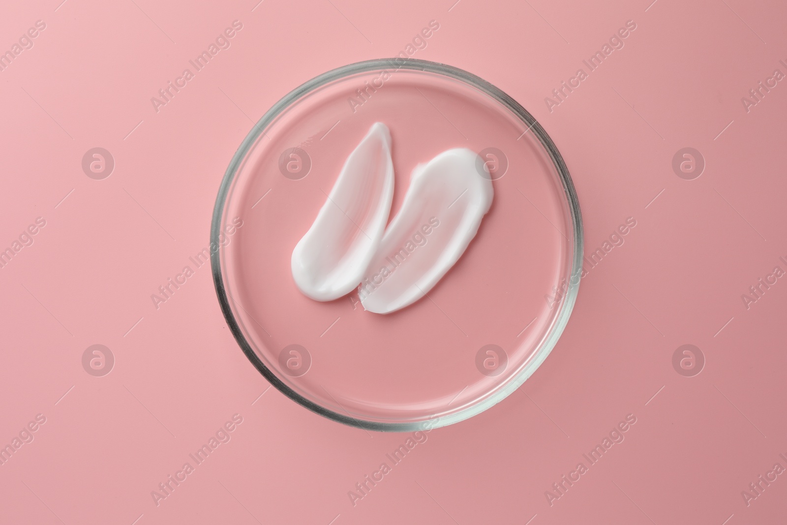 Photo of Petri dish with cosmetic product on pink background, top view