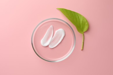 Photo of Petri dish with cosmetic product and leaf on pink background, flat lay