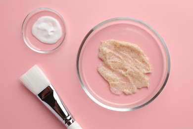 Photo of Petri dishes with cosmetic products and brush on pink background, flat lay