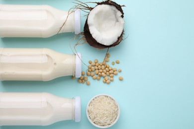 Photo of Different types of vegan milk in bottles and ingredients on light blue table, flat lay. Space for text