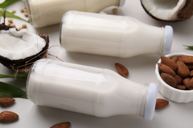 Photo of Different types of vegan milk in bottles and ingredients on light grey table, closeup