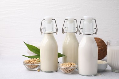 Photo of Different types of vegan milk and ingredients on light grey table