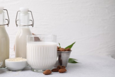 Different types of vegan milk and ingredients on light grey table, space for text