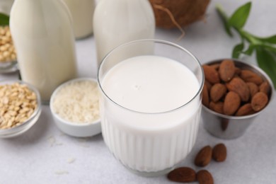 Different types of vegan milk and ingredients on light grey table, closeup