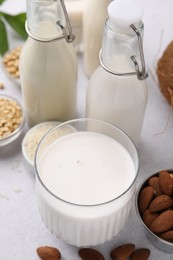 Photo of Different types of vegan milk and ingredients on light grey table, closeup