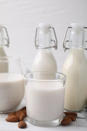 Different types of vegan milk and ingredients on white wooden table, closeup