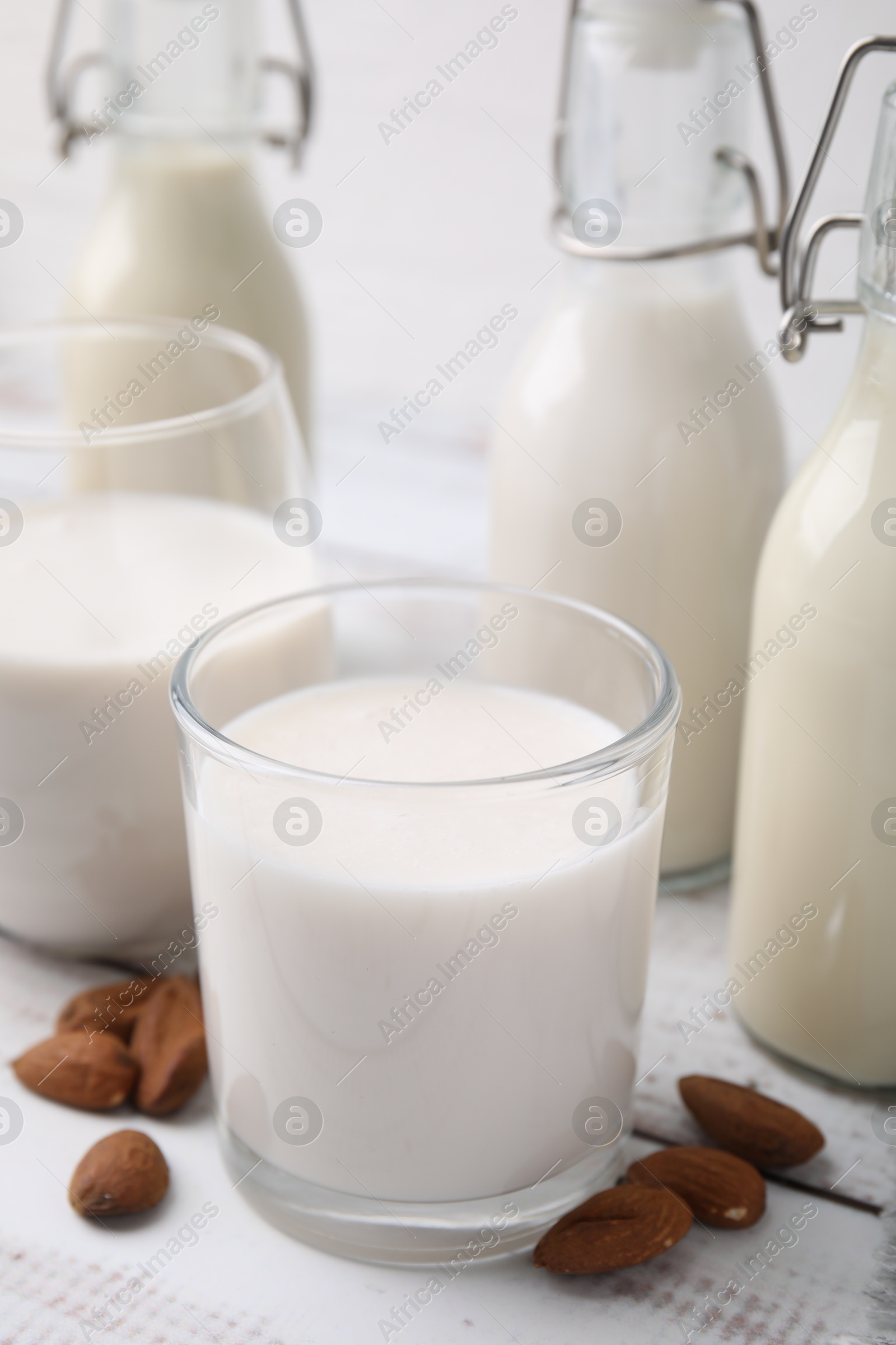 Photo of Different types of vegan milk and ingredients on white wooden table, closeup