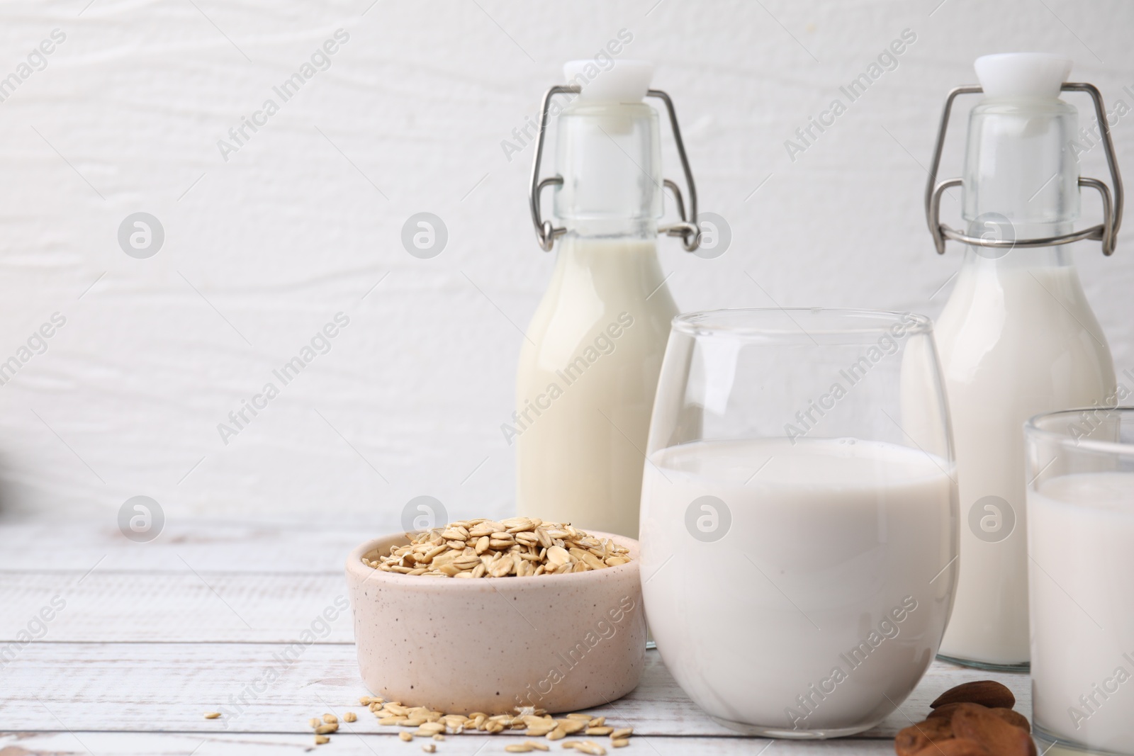 Photo of Different types of vegan milk and ingredients on white wooden table. Space for text