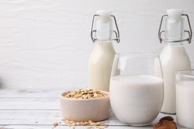 Photo of Different types of vegan milk and ingredients on white wooden table. Space for text