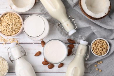 Photo of Different types of vegan milk and ingredients on white wooden table, flat lay