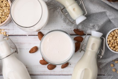 Photo of Different types of vegan milk and ingredients on white wooden table, flat lay