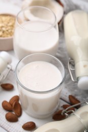 Photo of Different types of vegan milk and ingredients on white wooden table, closeup