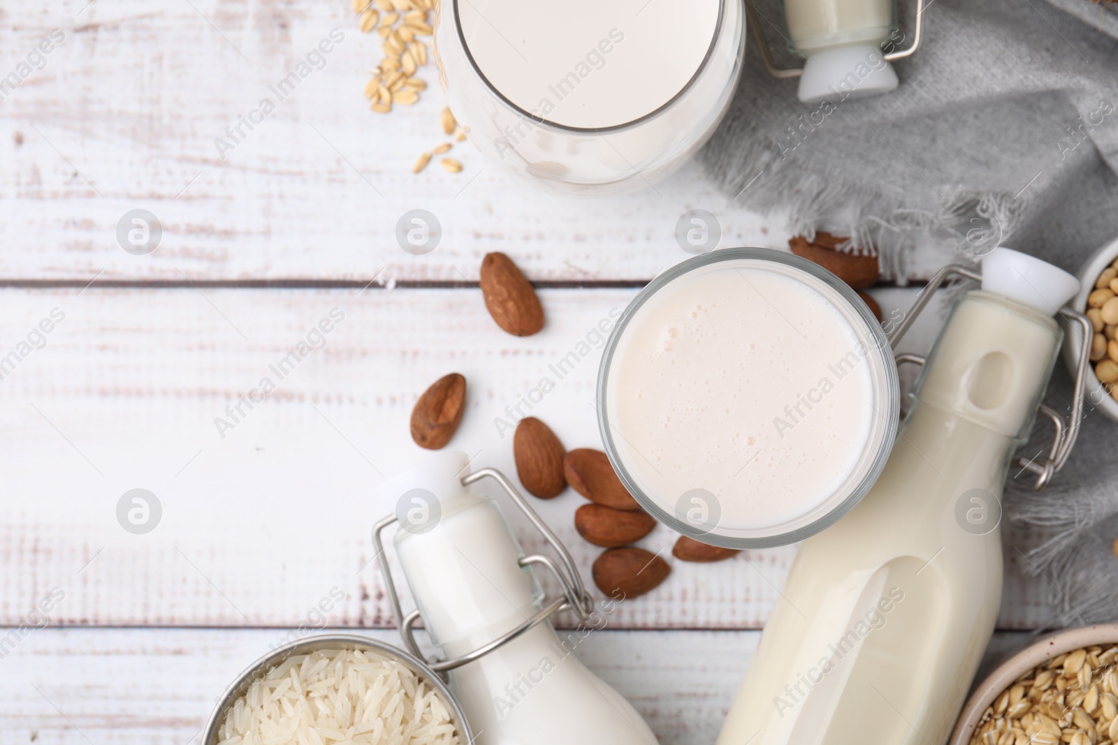 Photo of Different types of vegan milk and ingredients on white wooden table, flat lay. Space for text