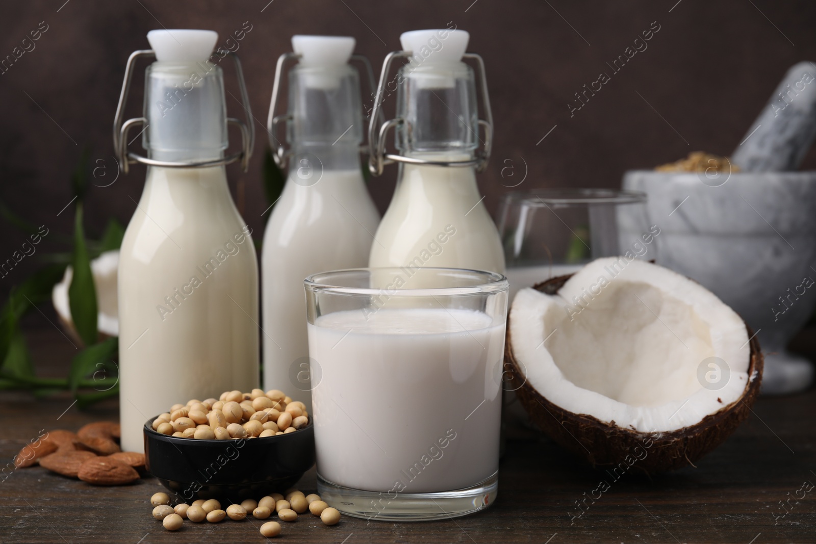 Photo of Different types of vegan milk and ingredients on wooden table