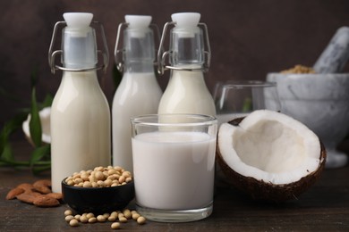 Different types of vegan milk and ingredients on wooden table