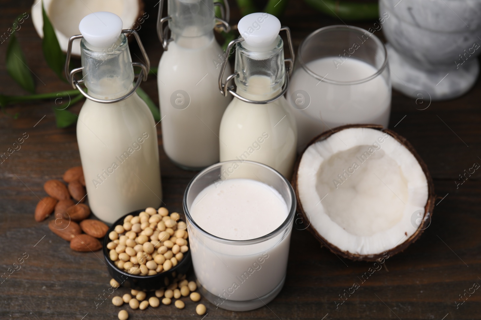 Photo of Different types of vegan milk and ingredients on wooden table