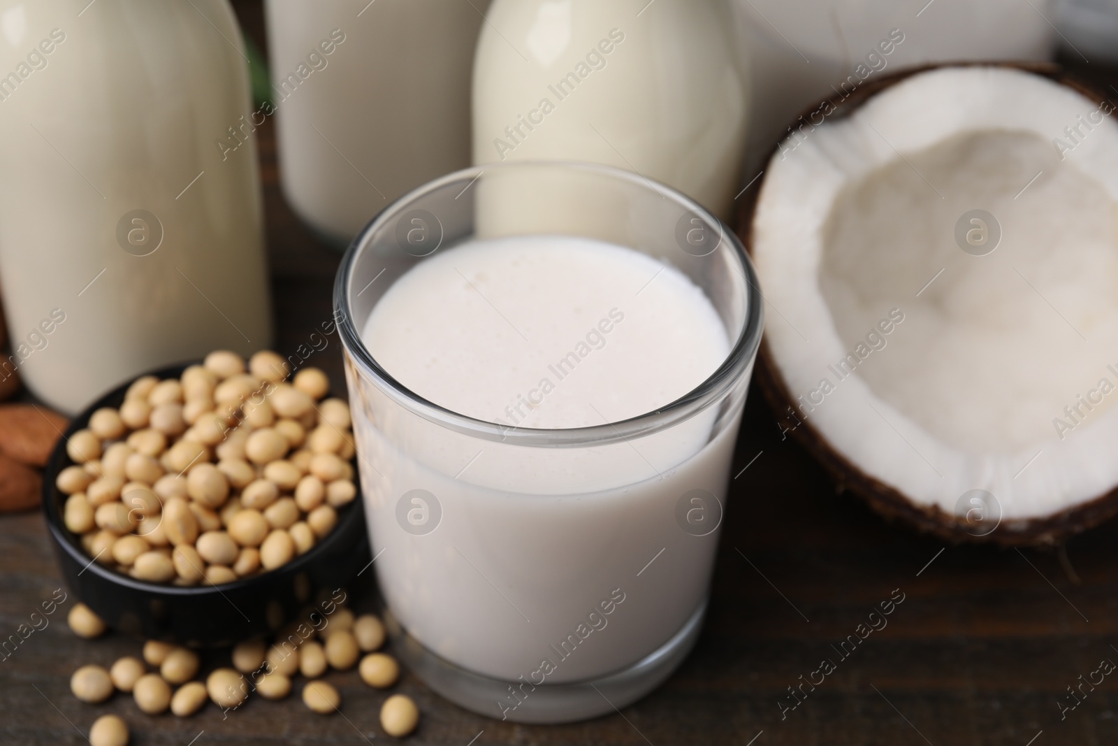 Photo of Different types of vegan milk and ingredients on wooden table, closeup