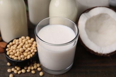 Photo of Different types of vegan milk and ingredients on wooden table, closeup