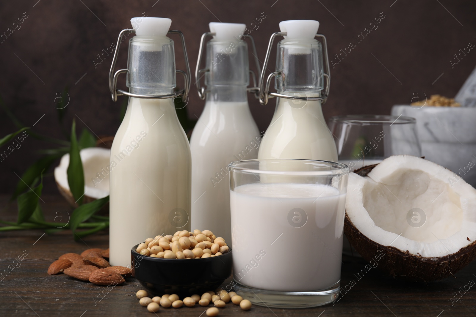 Photo of Different types of vegan milk and ingredients on wooden table