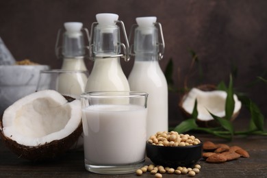 Photo of Different types of vegan milk and ingredients on wooden table