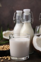 Photo of Different types of vegan milk and ingredients on wooden table