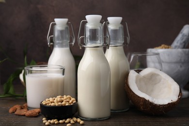 Different types of vegan milk and ingredients on wooden table