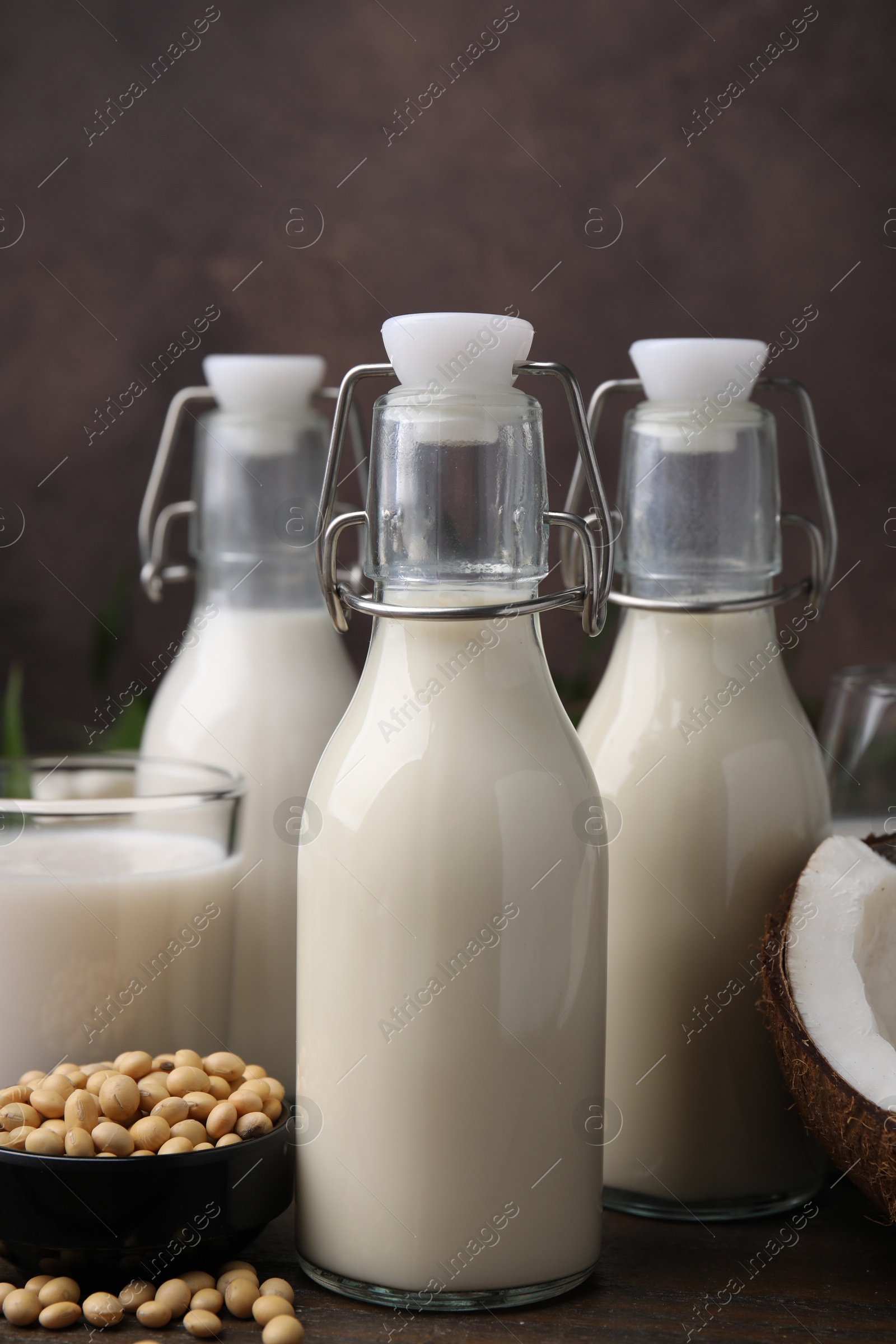 Photo of Different types of vegan milk and ingredients on wooden table