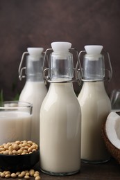 Photo of Different types of vegan milk and ingredients on wooden table