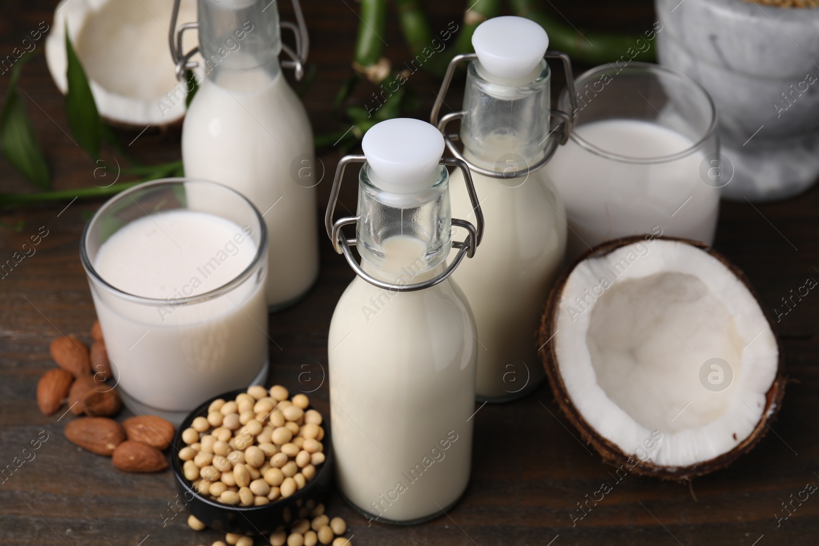 Photo of Different types of vegan milk and ingredients on wooden table