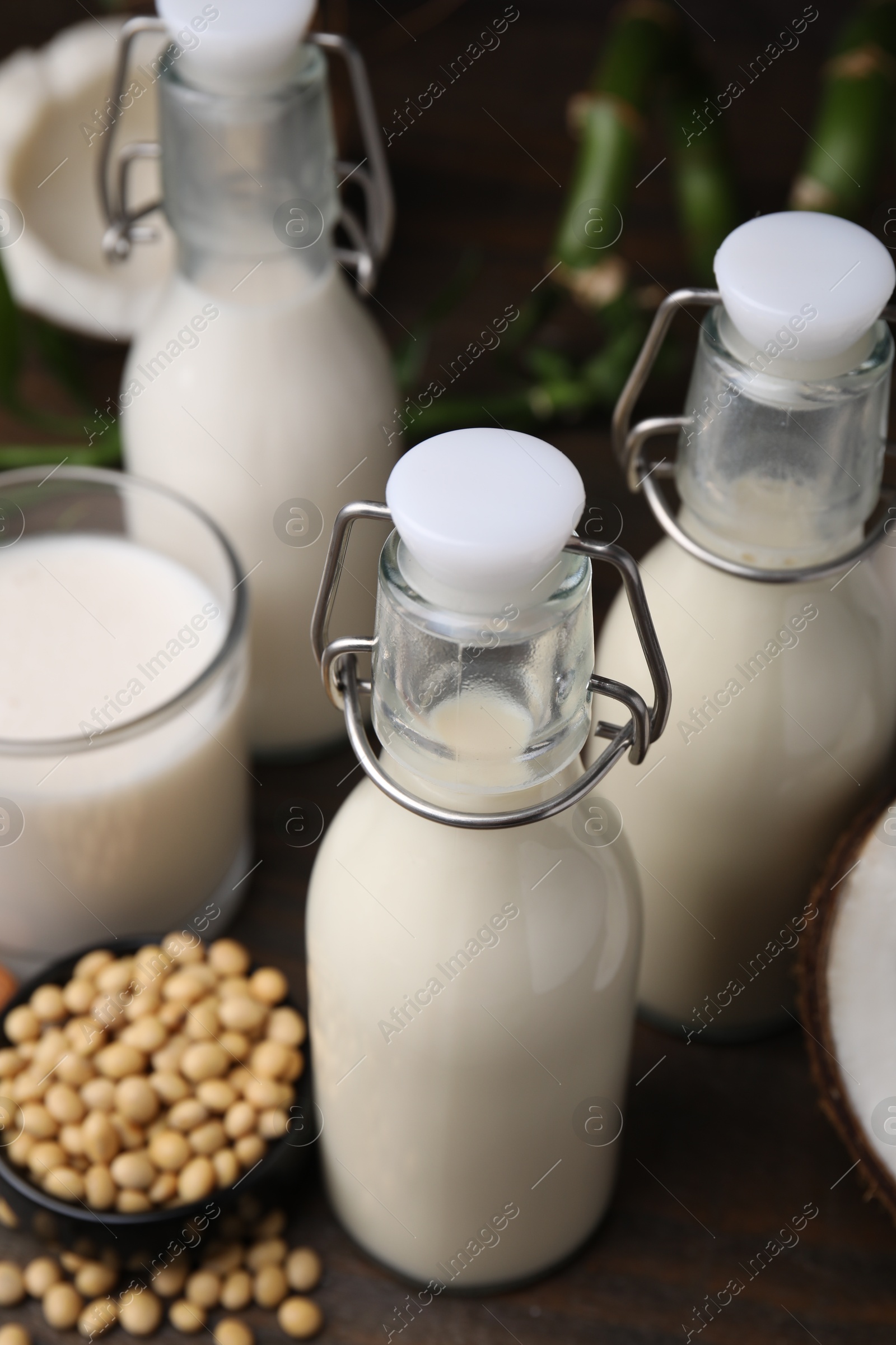 Photo of Different types of vegan milk and ingredients on wooden table