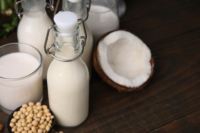 Photo of Different types of vegan milk and ingredients on wooden table, closeup