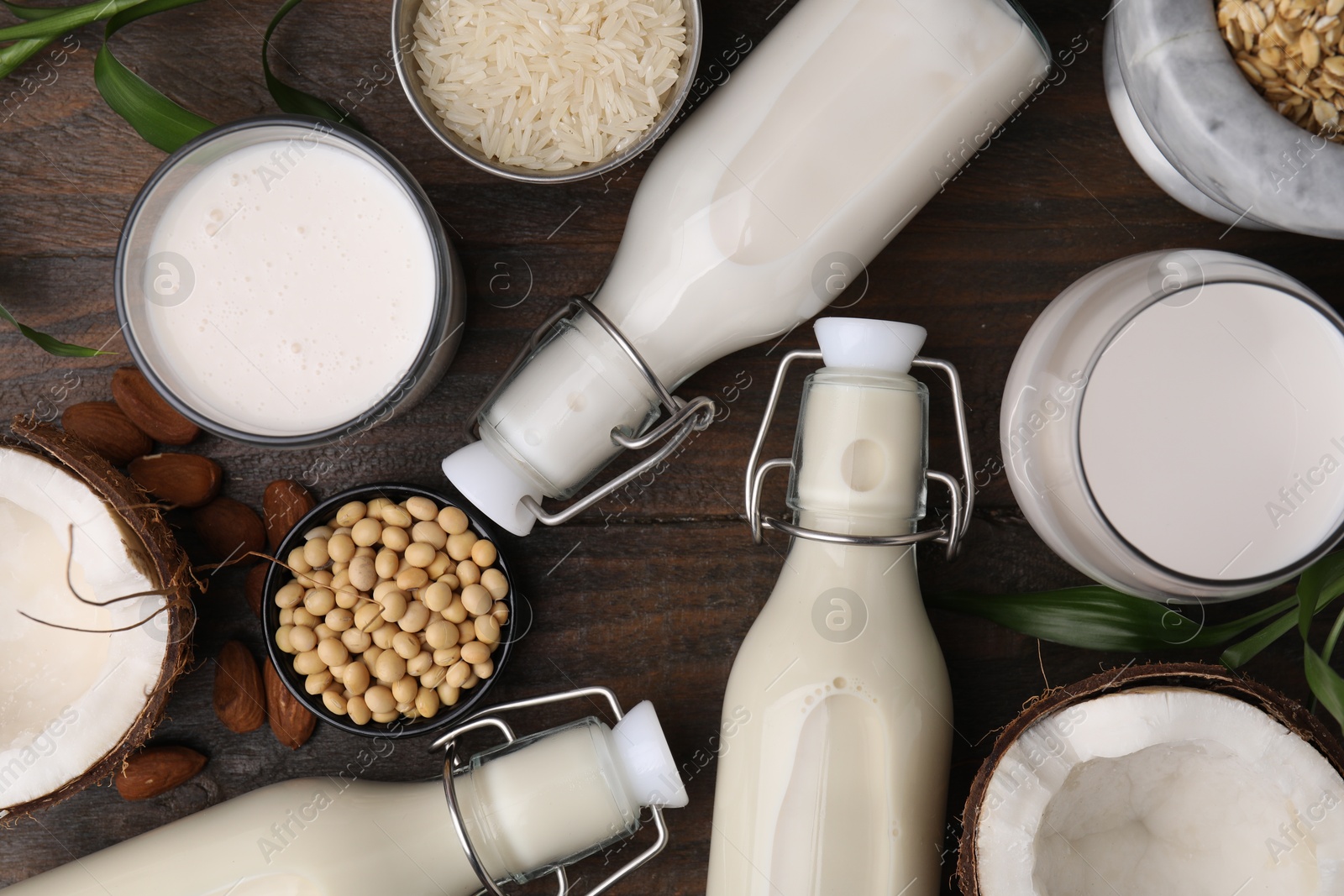 Photo of Different types of vegan milk and ingredients on wooden table, flat lay