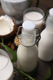 Photo of Different types of vegan milk and ingredients on wooden table, closeup