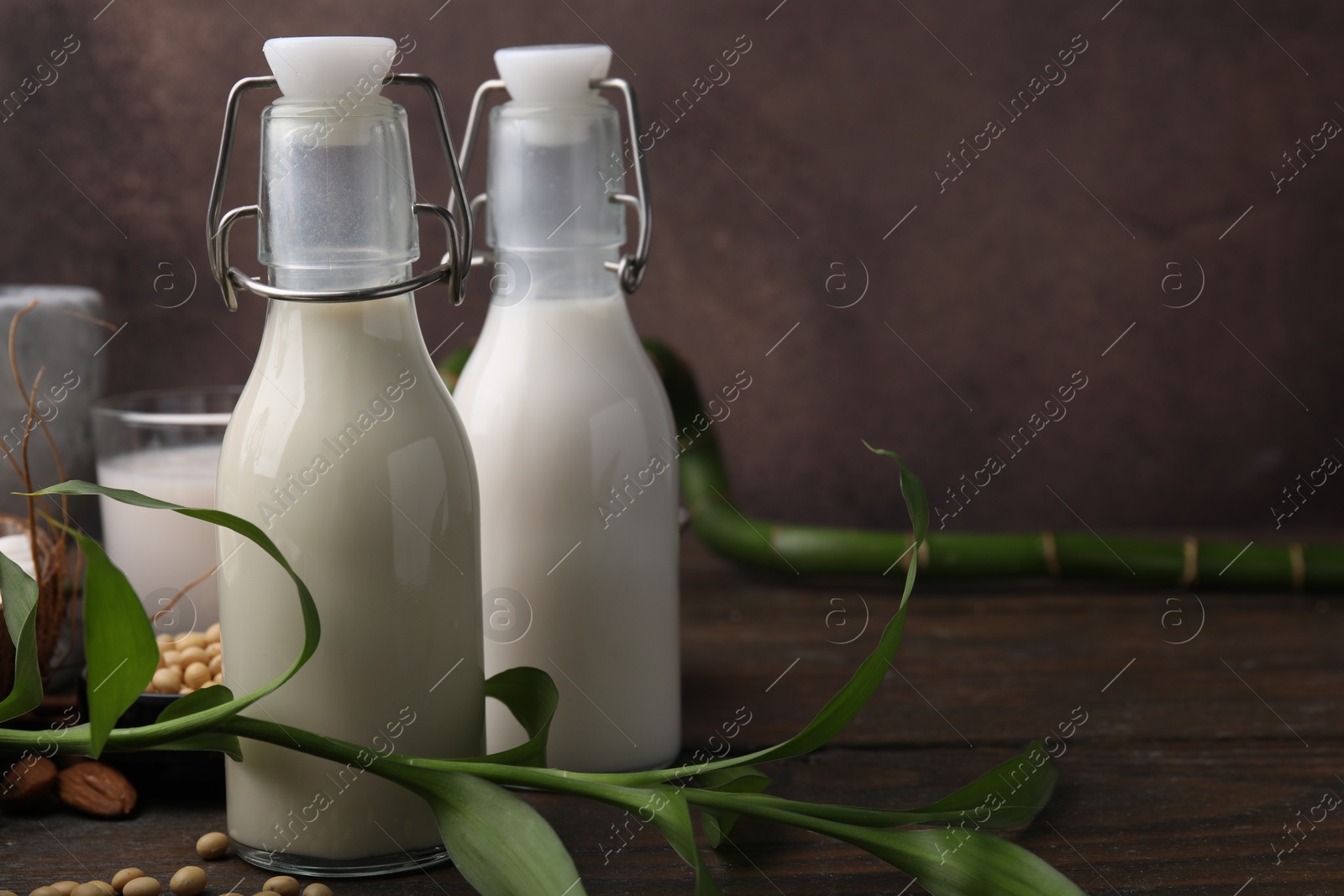 Photo of Different types of vegan milk and ingredients on wooden table