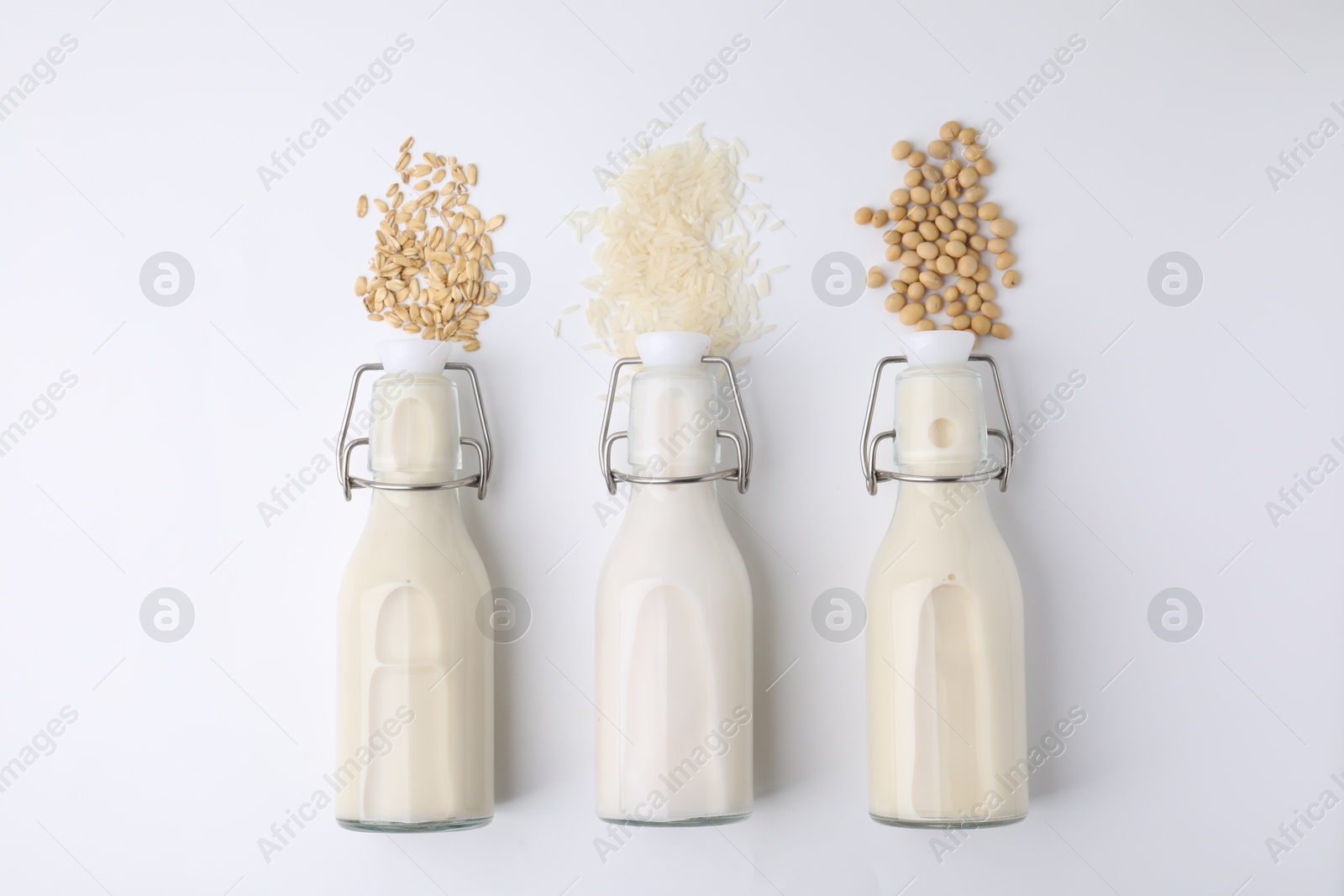 Photo of Different types of vegan milk and ingredients on white table, flat lay