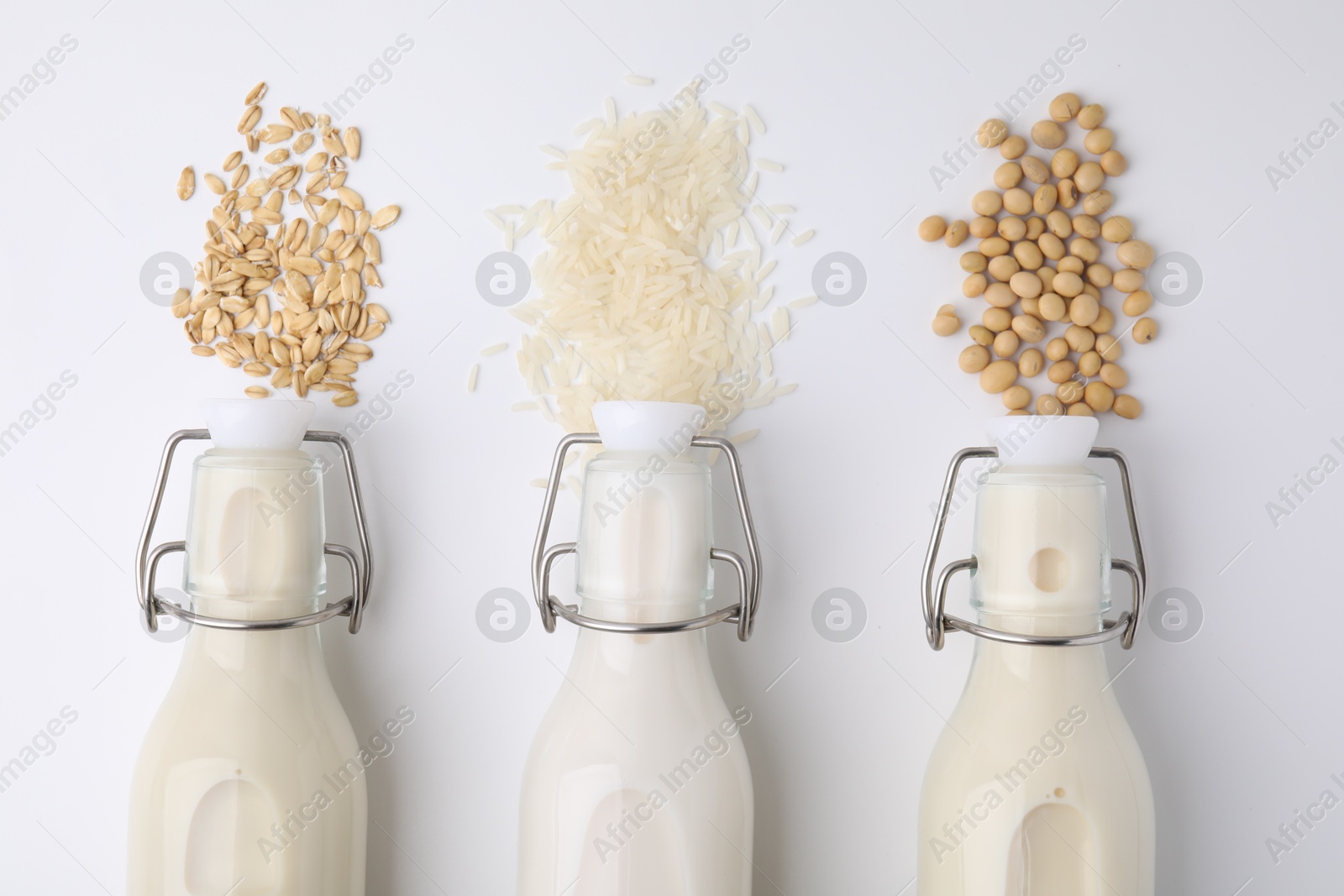 Photo of Different types of vegan milk and ingredients on white table, flat lay