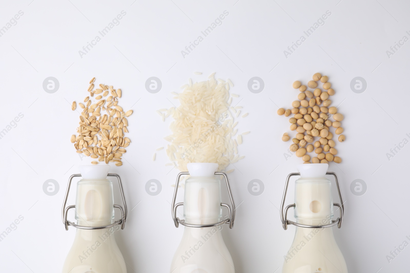 Photo of Different types of vegan milk and ingredients on white table, flat lay