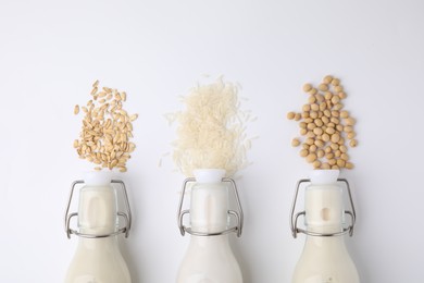 Photo of Different types of vegan milk and ingredients on white table, flat lay