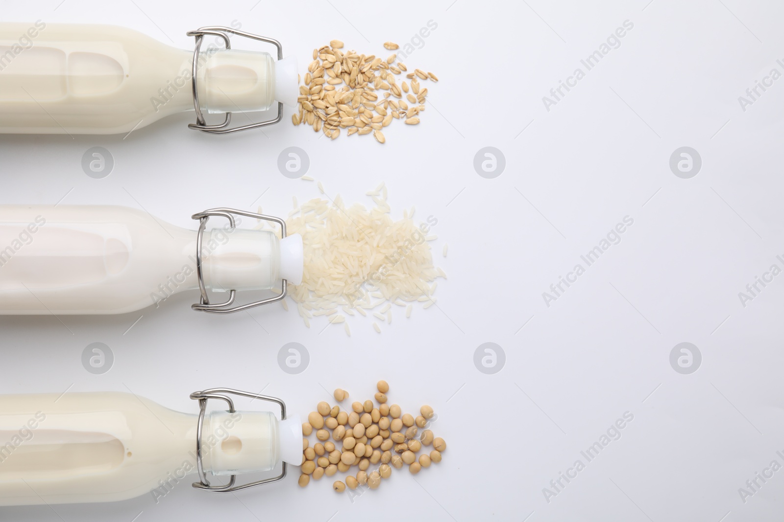 Photo of Different types of vegan milk and ingredients on white table, flat lay. Space for text