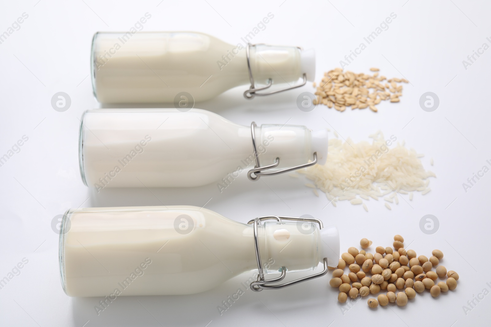 Photo of Different types of vegan milk and ingredients on white table