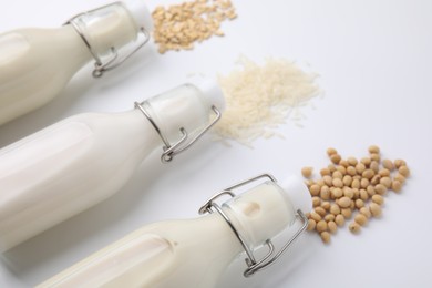 Photo of Different types of vegan milk and ingredients on white table, closeup